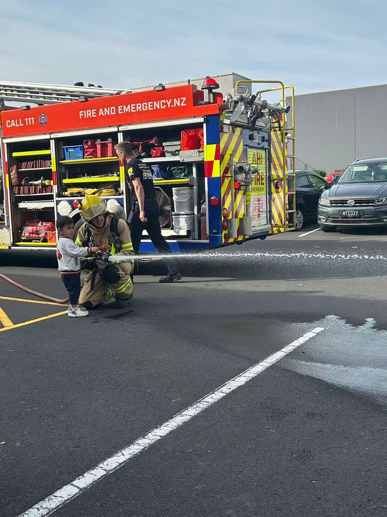 Firefighter demonstrating a hose with a child