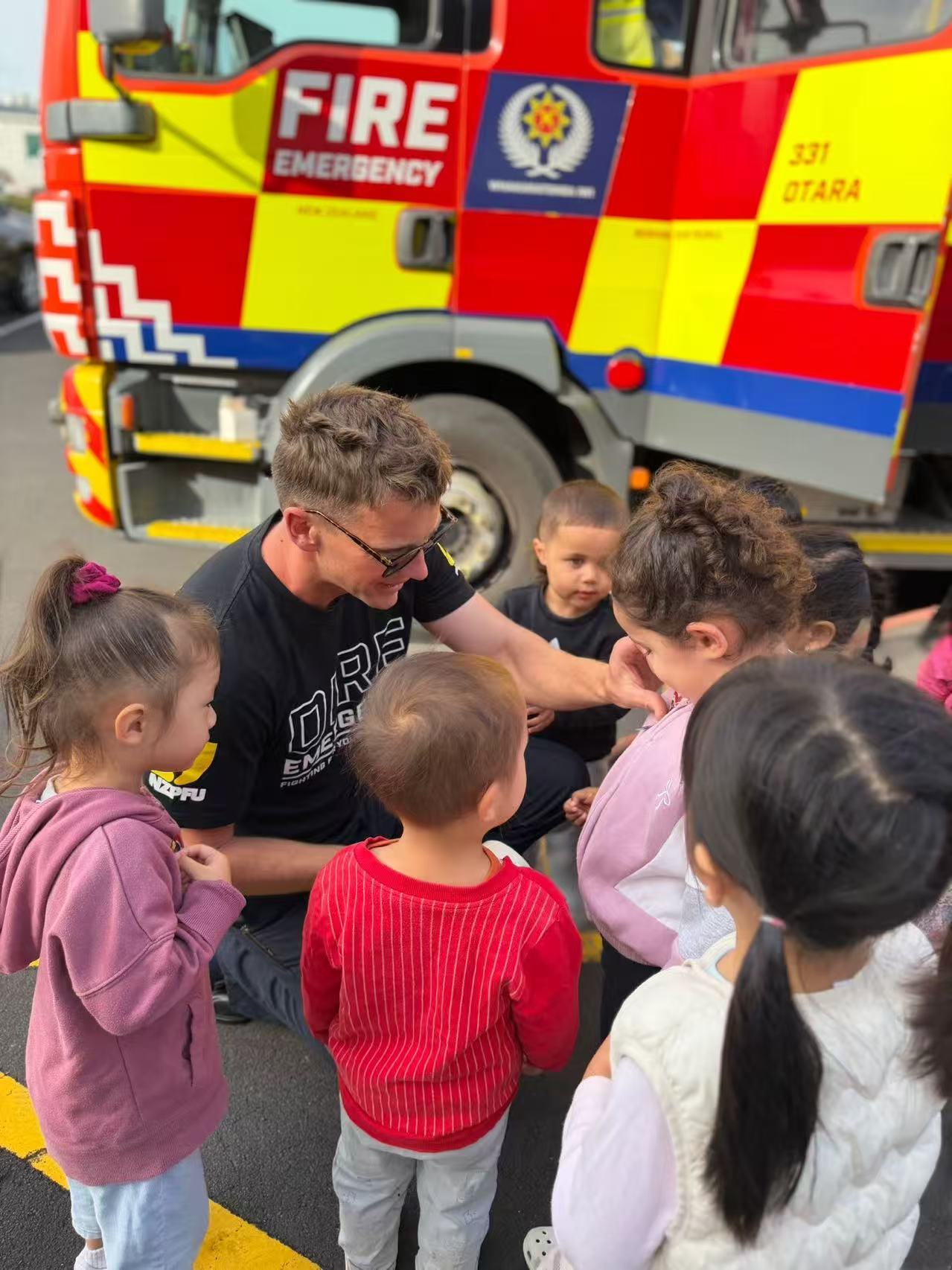 Children talking with a firefighter beside a fire truck